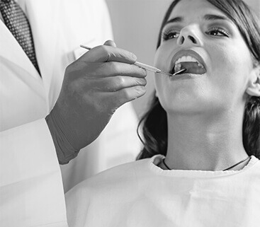 A Black and White Photo of a Female Patient Getting an Oral Dental Checkup