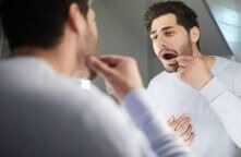 Man Checking His Teeth for Cavities or Damage in a Mirror